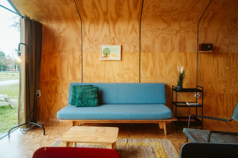 Salón moderno en la tiny house Wikkel con sofá azul y paredes de madera en De Klepperstee, Países Bajos.