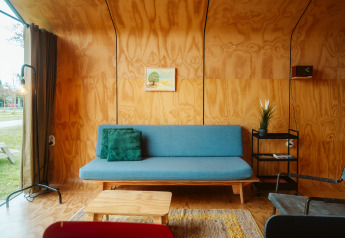 Moderne woonkamer in Wikkel tiny house met blauwe bank en houten muren bij De Klepperstee, Nederland.