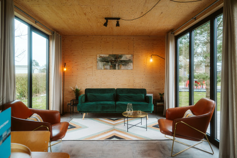 Modern lodge living room at Kleproos, Holiday park De Klepperstee, Netherlands, with large windows.