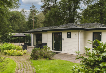 Naturhytte ved Bospark Markelo i Holland, omgivet af grønne træer, buske og haveområde.