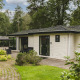 Naturhytte ved Bospark Markelo i Holland, omgivet af grønne træer, buske og haveområde.