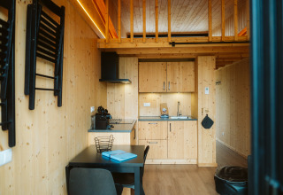 Moderne tiny house met houten keuken en eettafel bij vakantiepark De Klepperstee in Nederland.