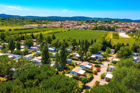 Aerial view of Camping Seasonova Ensoya holiday park in Occitanie, France, surrounded by lush green fields.