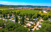 Luftfoto af Camping Seasonova Ensoya, en feriepark i Occitanie, Frankrig, omgivet af grønne marker og træer.