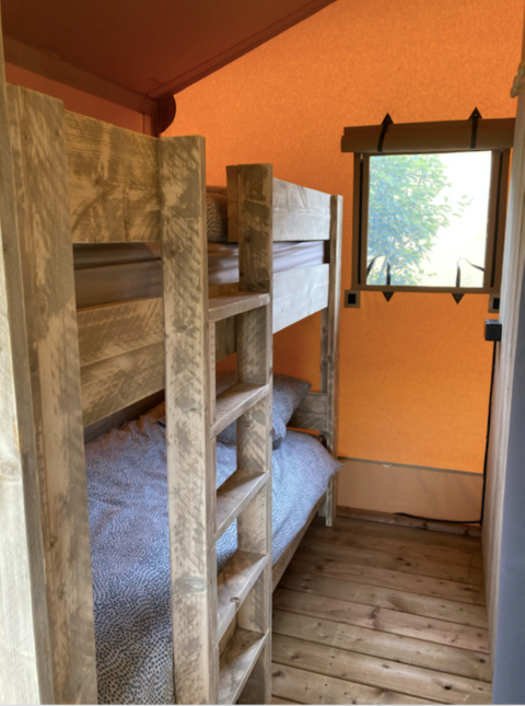 Literas de madera en una tienda safari en Wood Lodge, Camping Seasonova Ensoya, Francia, ventana al fondo.