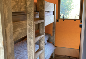 Wooden bunk beds inside a safari tent at Wood Lodge, Camping Seasonova Ensoya, France, window view.