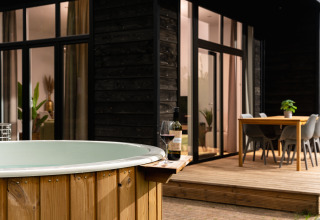 Bañera de hidromasaje y terraza exterior con copa de vino en Wellness Boutique, Holiday Park Mölke, Países Bajos.