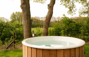 Udendørs badekar ved Wellness Boutique på Holiday Park Mölke, omgivet af træer og grønne marker.