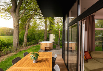 Buiteneettafel en hottub aan Wellness Boutique Lodge, Holiday Park Mölke, in het groen omgeven.