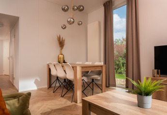 Zona pranzo e soggiorno moderna alla Wellness Boutique nel Holiday Park Mölke, Paesi Bassi, con vista giardino.
