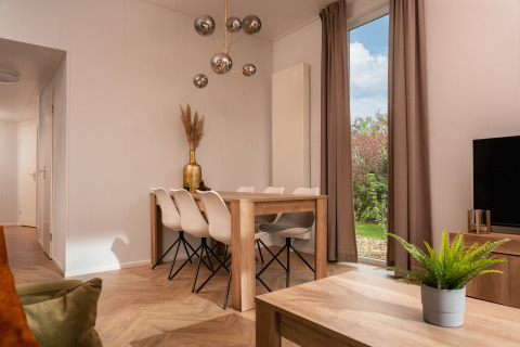 Moderne eet- en woonkamer in Wellness Boutique bij Holiday Park Mölke, Nederland, met uitzicht op de tuin.
