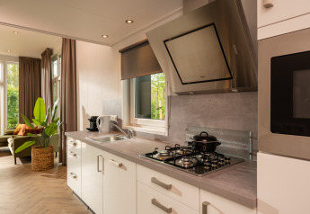 Cucina moderna con piano cottura a gas, cappa e ampie finestre in un lodge al Holiday Park Mölke, Paesi Bassi.