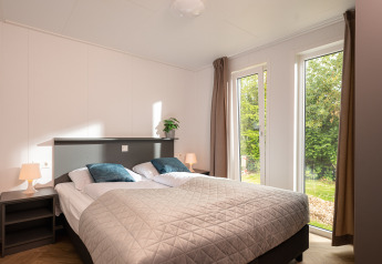 Helles Schlafzimmer mit Doppelbett, Fenster zum Garten, im Wellness Boutique Holiday Park Mölke, Niederlande.