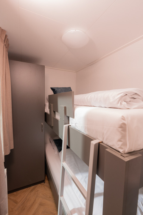 Moderne stapelbedden en een kast in een kleine kamer bij Wellness Boutique, Holiday Park Mölke, Nederland.