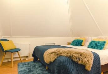 Sfeervolle slaapkamer in een lodge met tweepersoonsbed, blauwe en gele kussens bij Holiday Park Mölke.