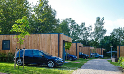 Groepsaccommodatie met lodges en hot tub, geparkeerde auto's bij Holiday Park Mölke, Nederland.