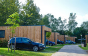 Group accommodation with hot tub lodges and parked cars at Holiday Park Mölke in the Netherlands.
