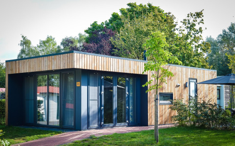 Moderne lodge med træfacade og store vinduer, omgivet af grønt, ved Holiday Park Mölke i Holland.