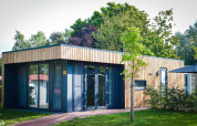 Lodge moderne en bois avec de grandes fenêtres, entouré de verdure, au Holiday Park Mölke aux Pays-Bas.
