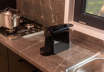 Moderne keuken met espressomachine, gasfornuis, pan en raam in Happy Oak Lodge bij Holiday Park Mölke.