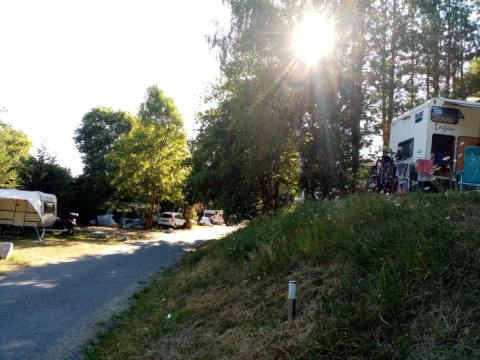 Sunny campsite with caravans and tents at Camping La Perle holiday park, Nouvelle-Aquitaine, France.