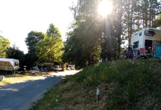 Sunny campsite with caravans and tents at Camping La Perle holiday park, Nouvelle-Aquitaine, France.