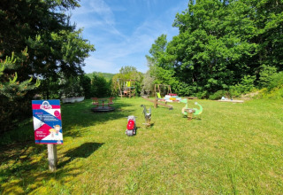Legeplads på Camping La Perle i Nouvelle-Aquitaine, Frankrig, omgivet af grønt og solskinsvejr.