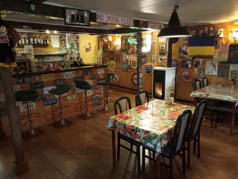 Cozy bar at Camping La Perle, Nouvelle-Aquitaine, France, decorated with license plates and various flags.
