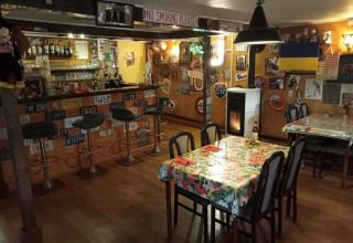 Cozy bar at Camping La Perle, Nouvelle-Aquitaine, France, decorated with license plates and various flags.