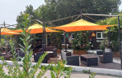 Udendørs siddeområde med gule og orange parasoller på Camping La Perle, en feriepark i Nouvelle-Aquitaine.