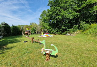 Legeplads på Camping La Perle i Nouvelle-Aquitaine, Frankrig, med gynger, vippe og grønt område.