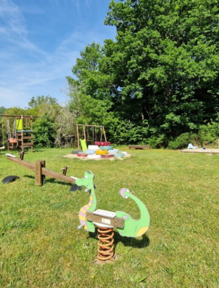 Legeplads på Camping La Perle i Nouvelle-Aquitaine, Frankrig, med gynger, vippe og grønt område.