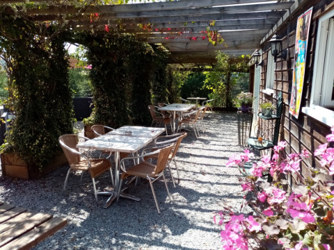 Outdoor seating area at Camping La Perle in Nouvelle-Aquitaine, France, with tables, chairs, and flowers.