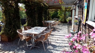 Udendørs siddeområde på Camping La Perle i Nouvelle-Aquitaine, Frankrig, med borde, stole og blomster.