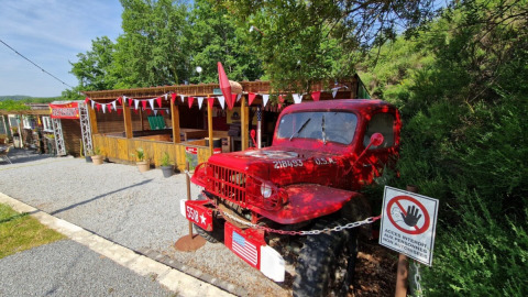 Camión clásico rojo en Camping La Perle, parque vacacional en Nouvelle-Aquitaine, Francia, junto a cabañas.