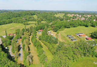 Luftfoto af Camping La Perle, en feriepark omgivet af grønne marker og skov i Nouvelle-Aquitaine, Frankrig.
