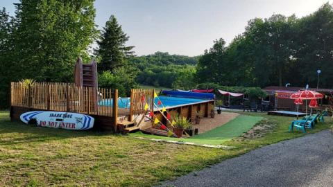 Area piscina all'aperto e relax presso Camping La Perle nel parco vacanze di Nouvelle-Aquitaine, Francia.