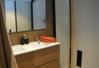 Moderne badkamer met houten wasmeubel, grote spiegel en handdoeken in Wander Lodge De Boshoek.