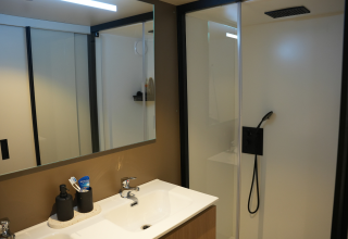 Moderne badkamer met dubbele lavabo en glazen douche in Wander Lodge bij De Boshoek vakantiepark, Nederland.