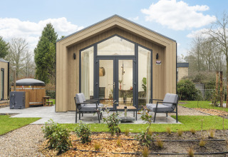 Tiny Lodge with hot tub at Veluwepark de Bosgraaf in the Netherlands, stylish tiny house with outdoor seating.