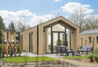 Modern Tiny Lodge with hot tub at Veluwepark de Bosgraaf, Netherlands, with garden and outdoor seating.