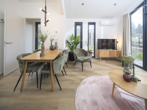 Cozy living and dining area inside Tiny Lodge with hot tub at Veluwepark de Bosgraaf, Netherlands.