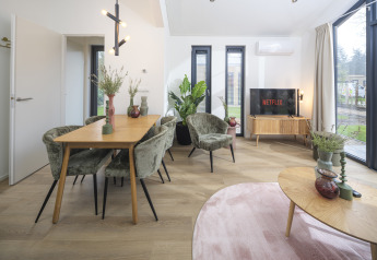 Cozy living and dining area inside Tiny Lodge with hot tub at Veluwepark de Bosgraaf, Netherlands.