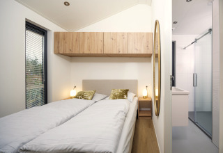 Dormitorio en Tiny Lodge con dos camas individuales y decoración moderna en Veluwepark de Bosgraaf, Países Bajos.