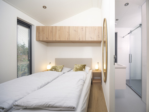 Dormitorio en Tiny Lodge con dos camas individuales y decoración moderna en Veluwepark de Bosgraaf, Países Bajos.