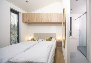 Bedroom inside Tiny Lodge at Veluwepark de Bosgraaf, Netherlands, with two single beds and modern wooden decor.