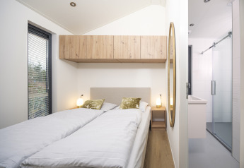 Soveværelse i Tiny Lodge med to enkeltsenge, lyse farver og moderne indretning på Veluwepark de Bosgraaf, Holland.