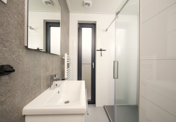 Modernes Badezimmer mit Dusche, Waschbecken und Fenster in der Tiny Lodge bei Veluwepark de Bosgraaf.