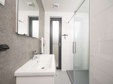 Modern bathroom with shower, sink, and window at Tiny Lodge with hot tub, Veluwepark de Bosgraaf, Netherlands.