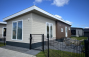 Moderne chalet ved navn Sea bass på Vakantiepark de Zeeuwse Parel i Holland, omgivet af hegn og græs.